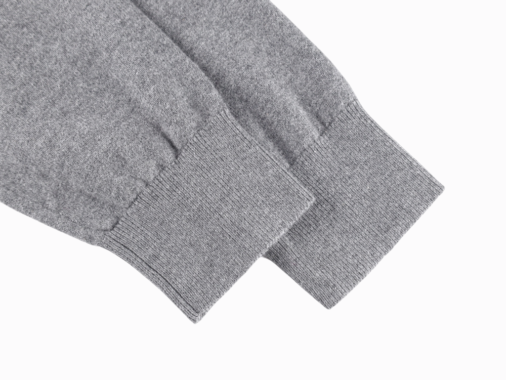 Gray sweater sleeves made from soft knit material, elegantly angled, showcasing ribbed cuffs on a flat, white background.