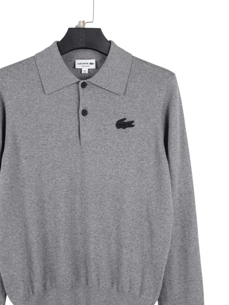 Close-up of soft gray fabric with textured weave and neutral tones, featuring a white care label positioned at an angle.