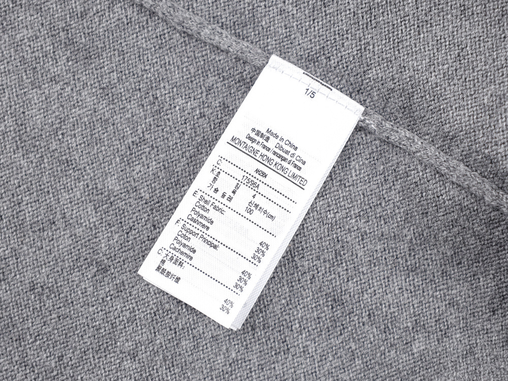 Close-up of a gray fabric with a care label. The material appears soft, with a textured weave in neutral tones.