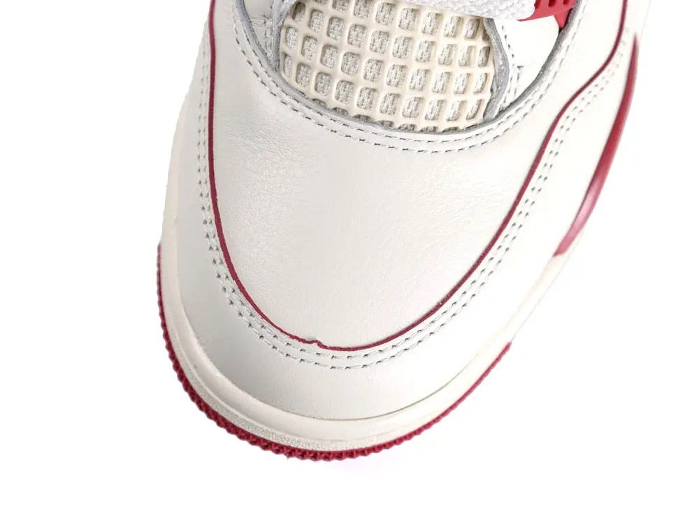 White leather sneaker with red trim and mesh detailing on the upper.
