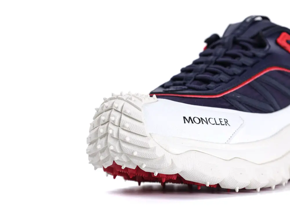 Navy and white sneaker with a red accent, textured rubber sole, and fabric upper.