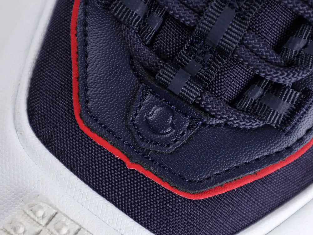 Close-up of navy and red fabric and leather sneaker with white textured sole.