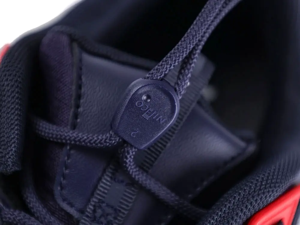 Navy blue fabric sneaker detail with plastic toggle and synthetic material parts.