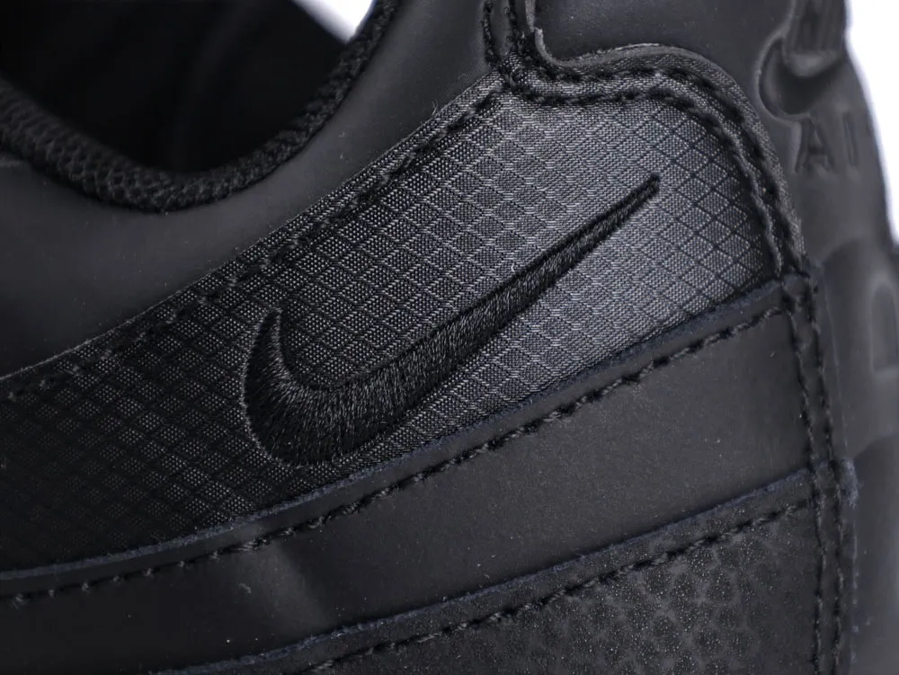 Close-up of black sneaker, showing synthetic textured fabric with an embroidered logo.