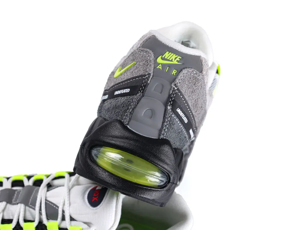Gray and black sneaker with neon accents, suede and leather materials, visible Air sole.