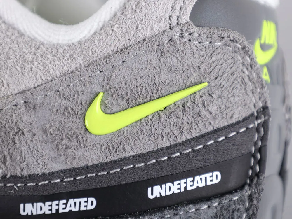 Gray suede sneaker heel with neon green logo and black rubber accent detail.