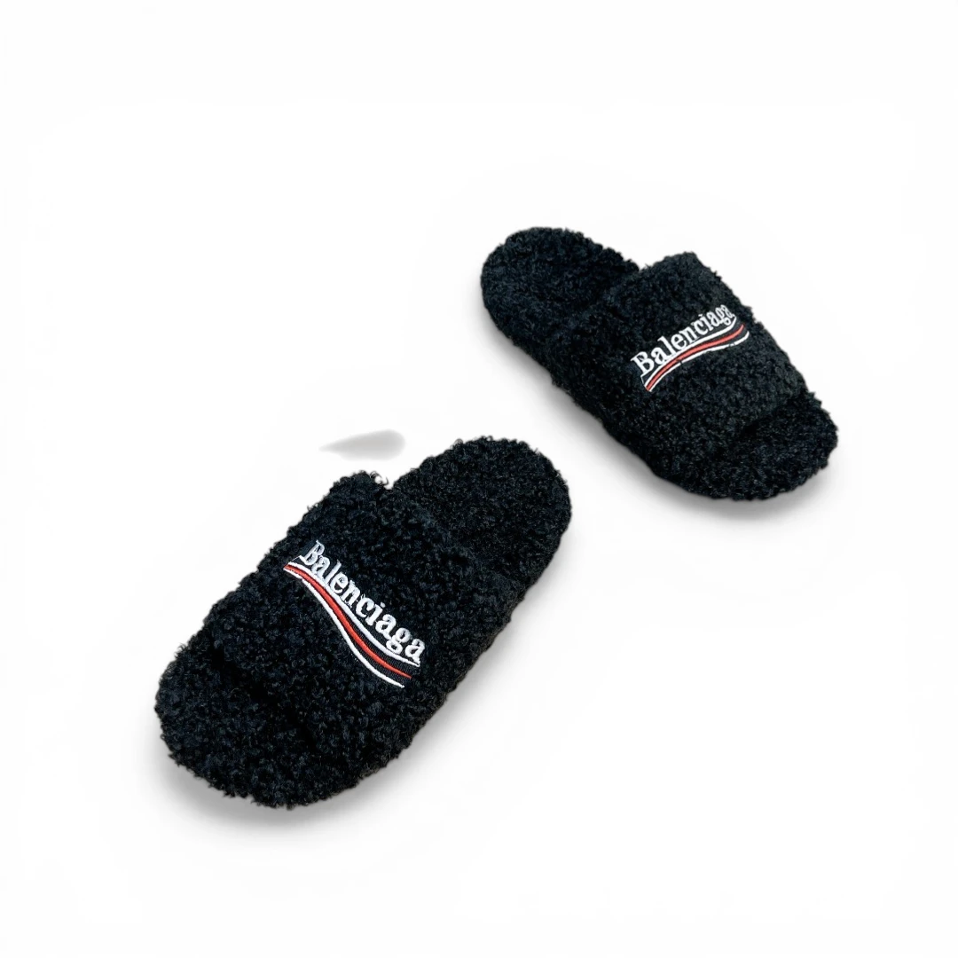 Black fuzzy slippers with embroidered logo, made from soft textured material.