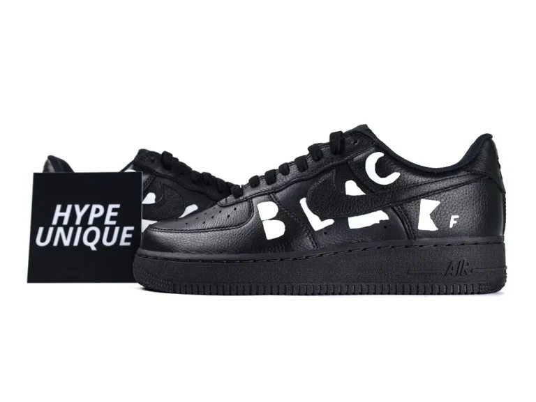 Black leather sneakers with textured surface and white letter accents on the side.