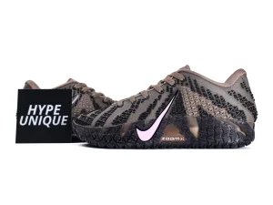 Tan and black knit sneakers with pink swoosh and textured black sole.