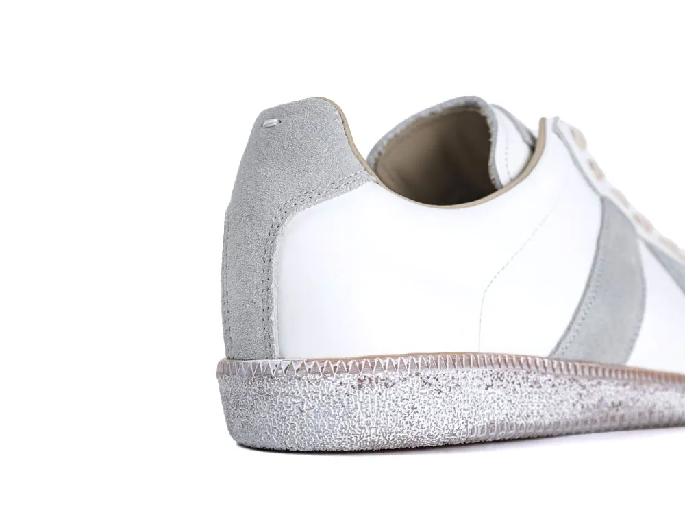 White leather sneaker with gray suede accents and textured sole, rear view.