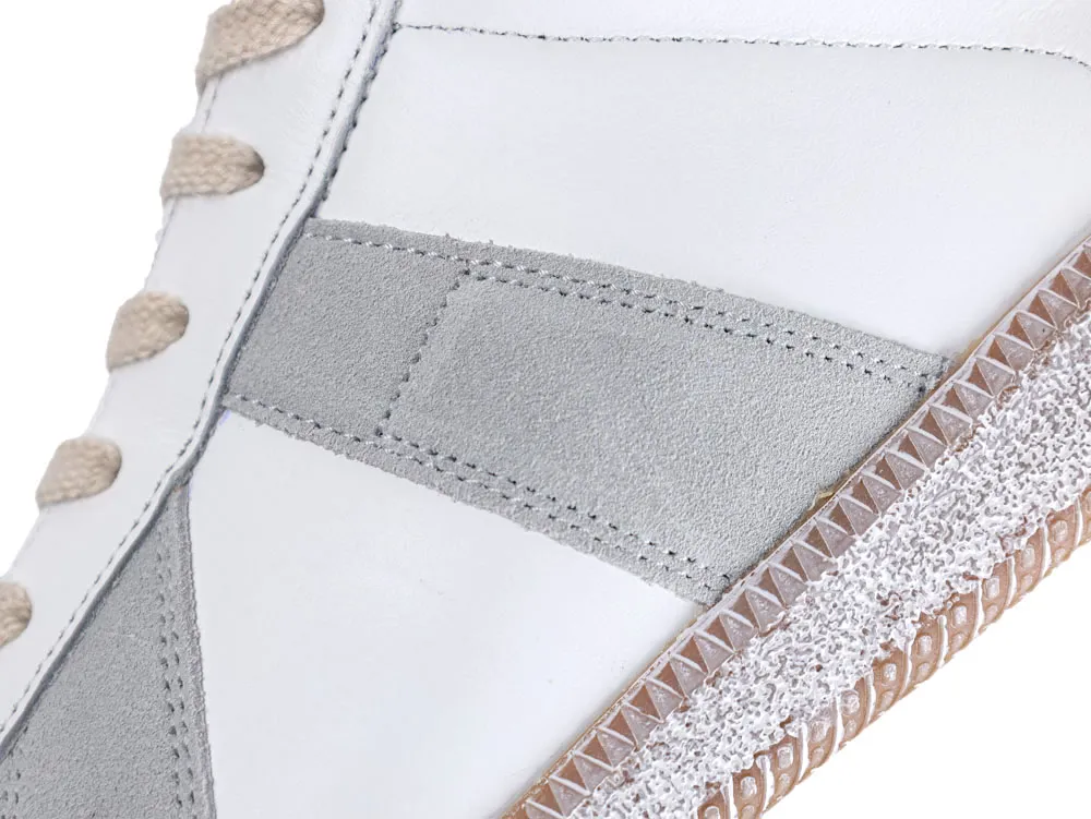 White and gray leather sneaker with beige laces and textured brown sole.