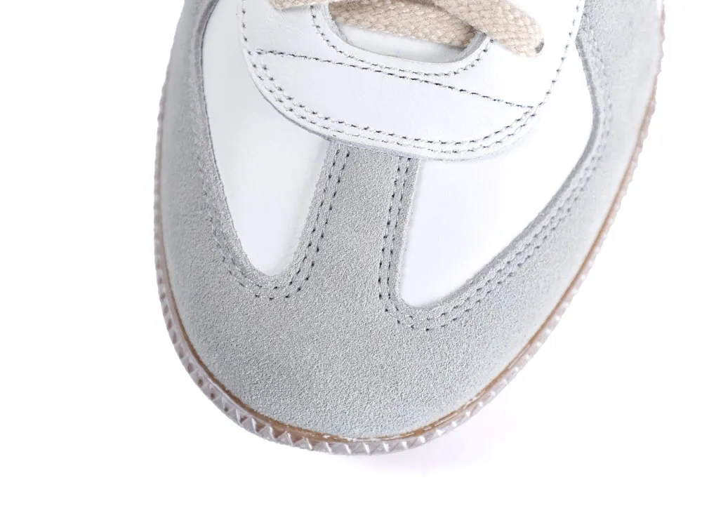 Close-up of a gray suede and white leather sneaker toe with beige laces.