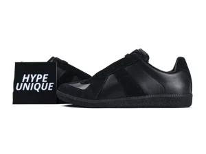 Black leather and suede sneakers with a rubber sole, displayed with a box.