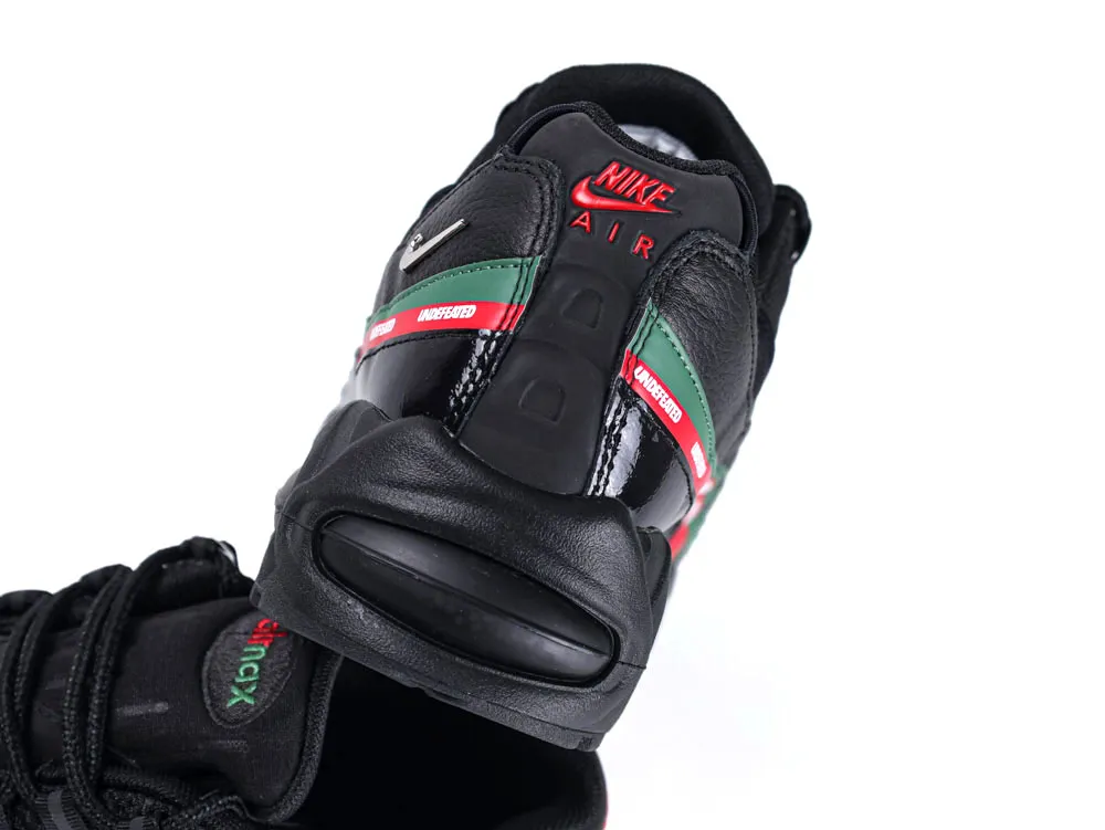 Black leather sneaker with green and red accents, featuring embroidered branding on heel.