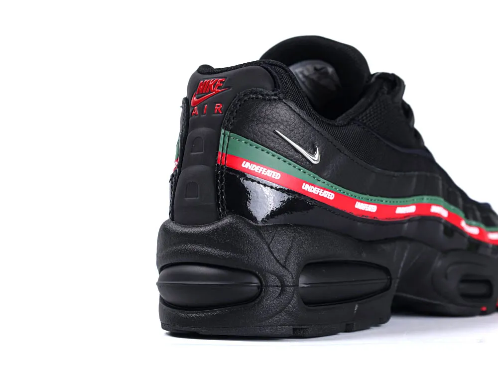 Black leather sneaker with green and red accents, featuring textured sole and branding.
