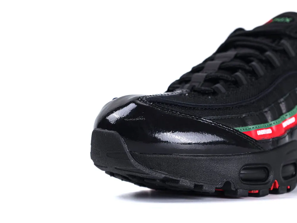 Black sneaker with glossy finish, mesh material, and green-red accents on the side.