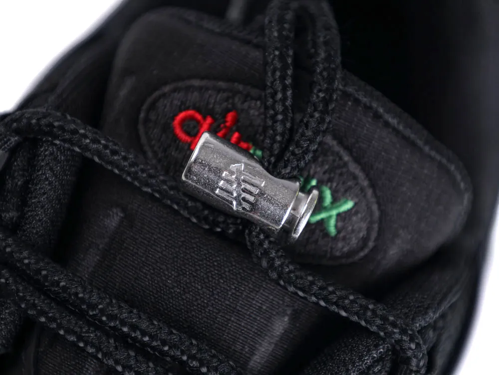 Metal lace lock on black fabric shoe with embroidered red and green lettering.