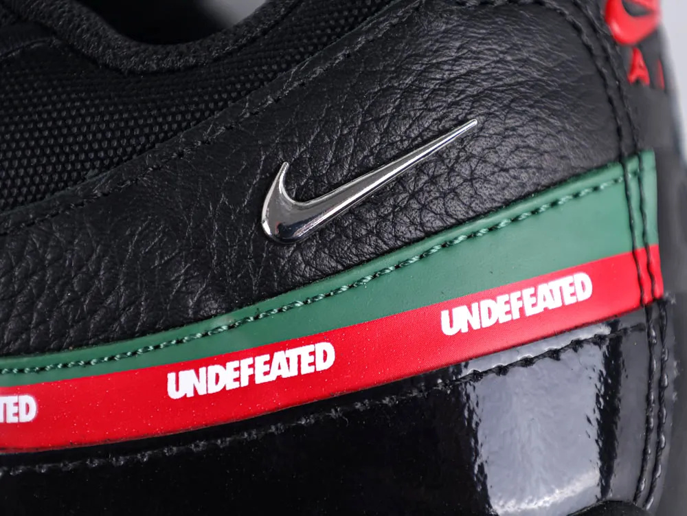 Black leather sneaker with silver logo, green and red trim, and patent accents.