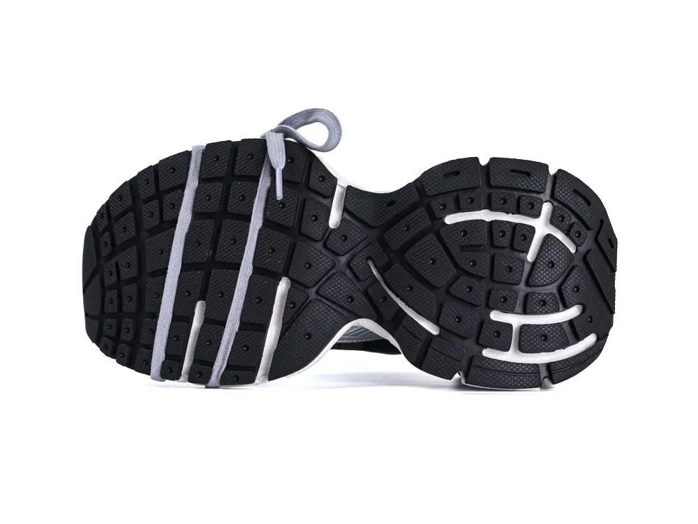 Black rubber shoe sole with white accents, showing textured treads and grey laces.