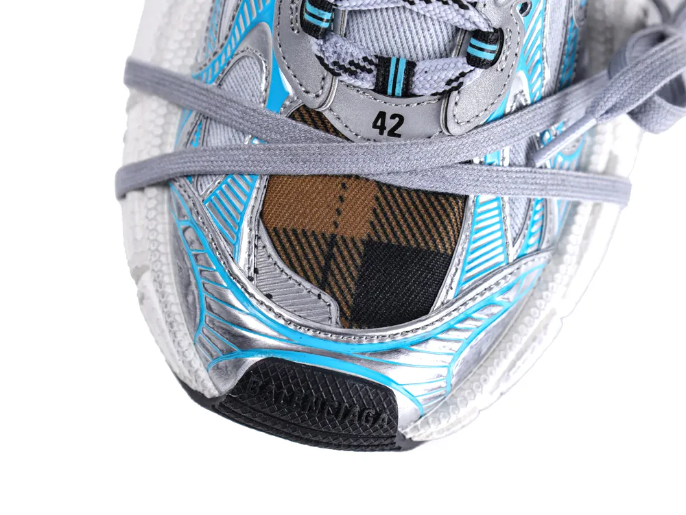 Close-up of a sneaker's front with blue, silver, and plaid fabric detailing.