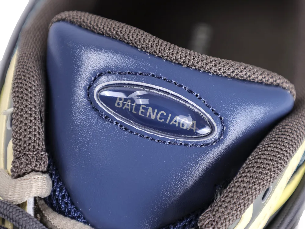 Blue leather tongue of a shoe with a logo, surrounded by brown fabric.