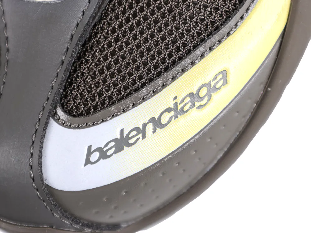 Close-up of a black mesh and leather sneaker with yellow trim and logo.