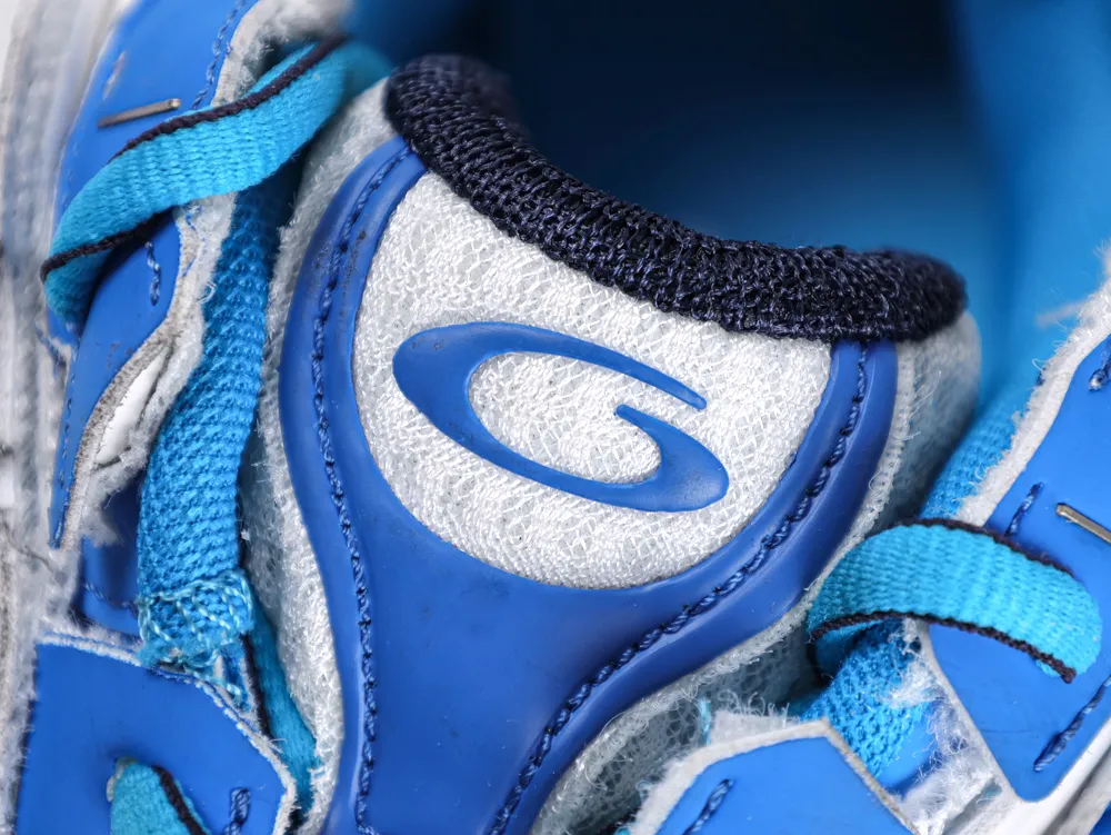 Close-up of a blue sneaker tongue with logo, featuring fabric and rubber materials.