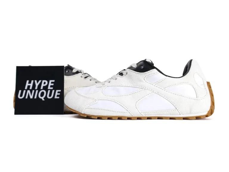 White and black suede sneakers with gum soles displayed beside a "Hype Unique" sign.