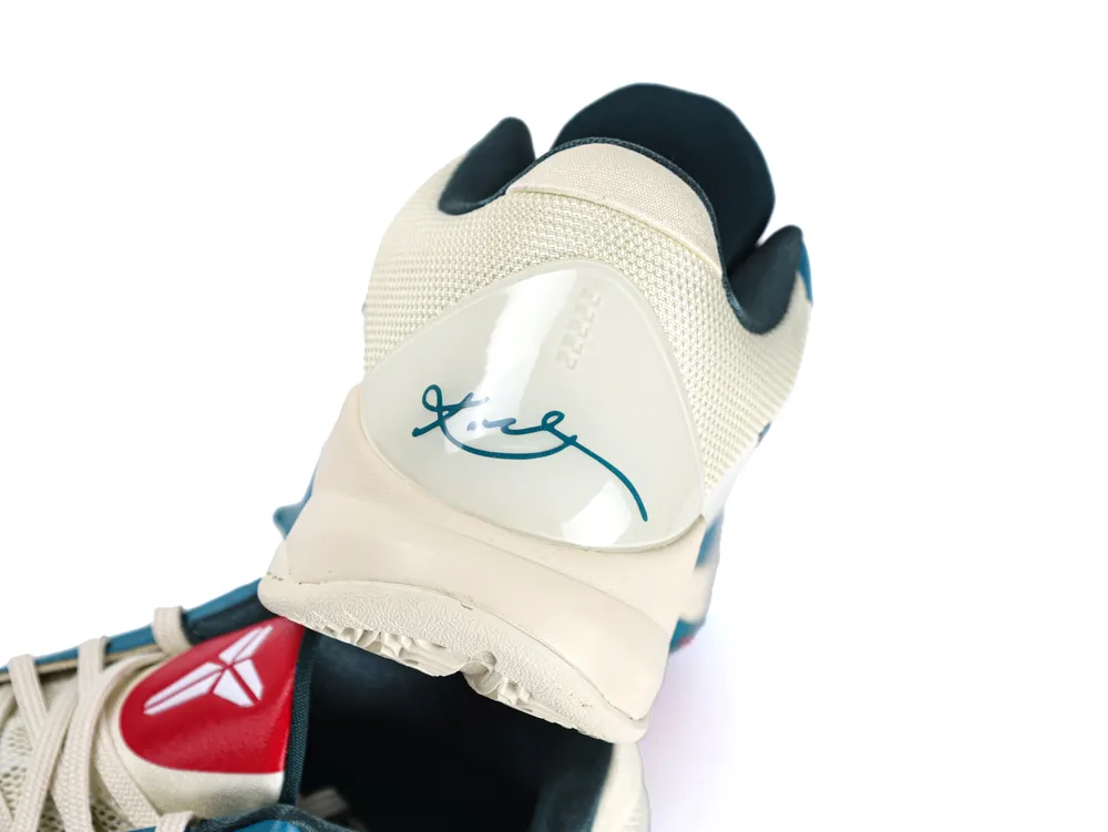 Beige mesh sneaker with white heel and teal signature detail.