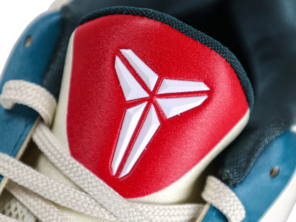 Close-up of a sneaker's red leather tongue with white logo and blue accents.
