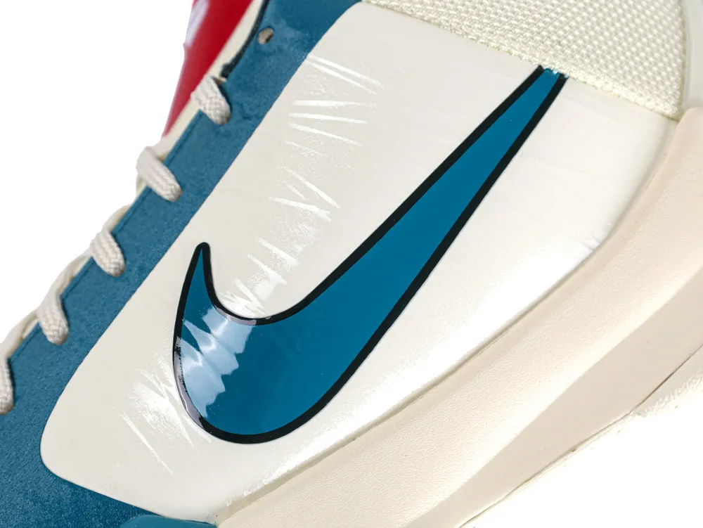 Close-up of a sneaker with blue logo, white leather, and beige sole.