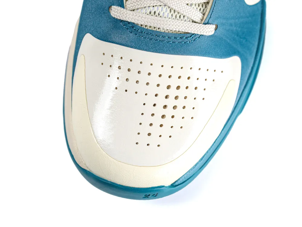 Close-up of a blue and white leather shoe toe with perforated design.