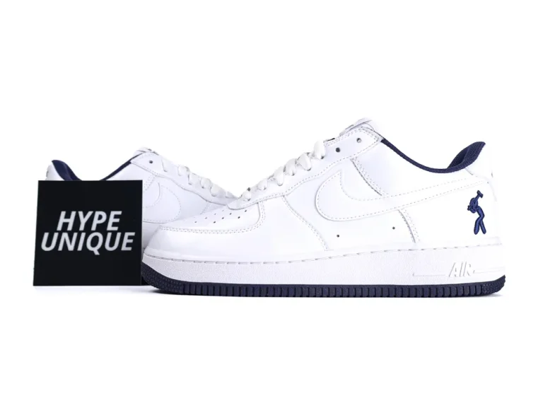 White leather sneakers with dark blue detailing, seen from the side.