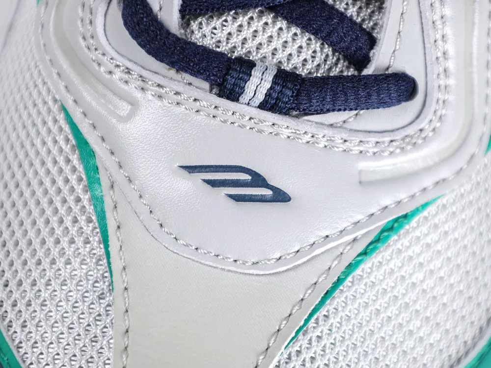 Close-up of the grey leather tongue featuring a dark blue embossed "B" logo and navy blue laces.