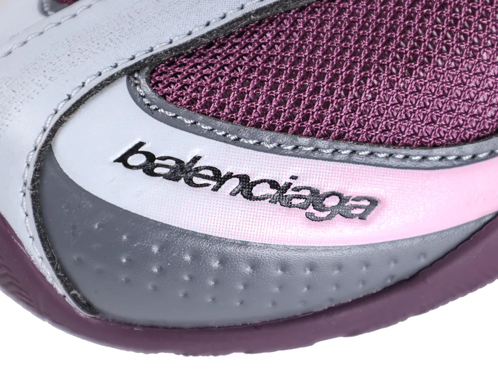 Macro close-up of the Balenciaga logo on the toe box, highlighting the perforated grey leather and pink stitching details.