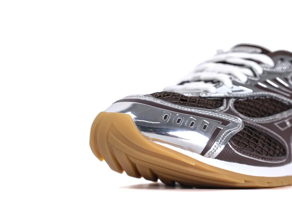 Close-up of a sneaker featuring a brown mesh upper and shiny silver accents.